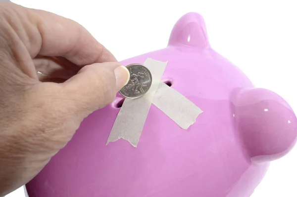 ピンクの貯金箱の底に穴からコインを引く女性の手の横のクローズアップショット — ストック写真