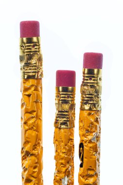 Beyaz arka planda çiğnenmiş üç kalemin silgisinin dikey yakın çekimi. Boşluğu Kopyala.