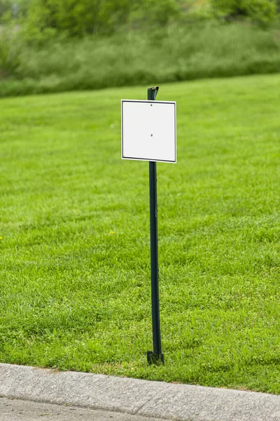 緑の芝生の庭の前に白い看板の垂直ショット — ストック写真