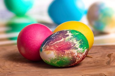 Tahtaya yakın plan üç yumurta, arka plan bulanık, kırmızı, sarı ve Paskalya yumurtaları.