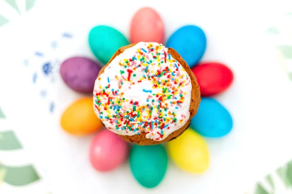 Easter cake surrounded by colored eggs on a table with a white napkin, focus on Easter cake, blurred background