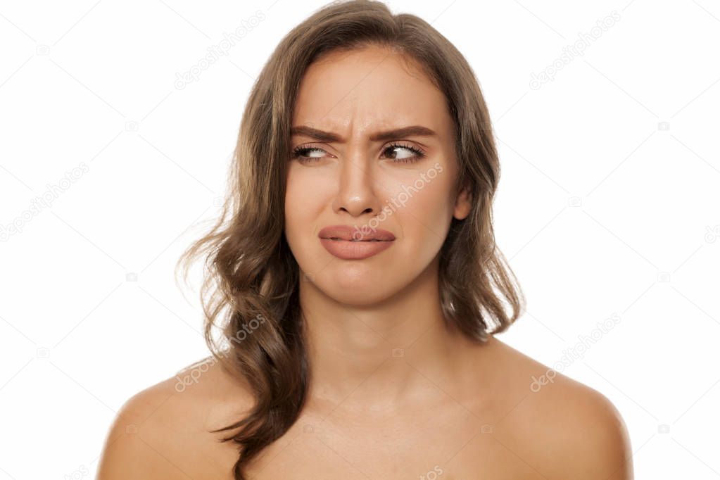 Beautiful young disgusted woman on a white background