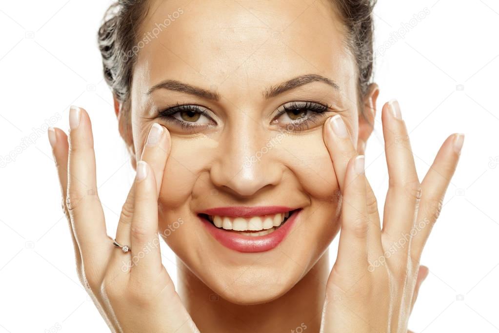 Young beautiful woman applying concealer under her eyes with her fingers