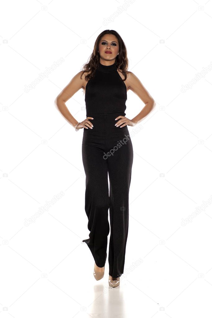 Woman in black sleeveless jumpsuit walking on a white background