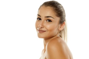 Beyaz bir arka plan üzerinde poz çıplak omuz ile genç gülümseyen kadın