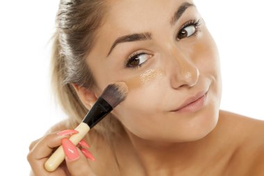 Genç güzel kadın sıvı bir fırça ile temel uygulama 