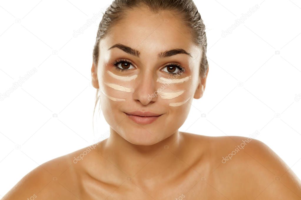 Young woman posing with corrective concealer under her eyes