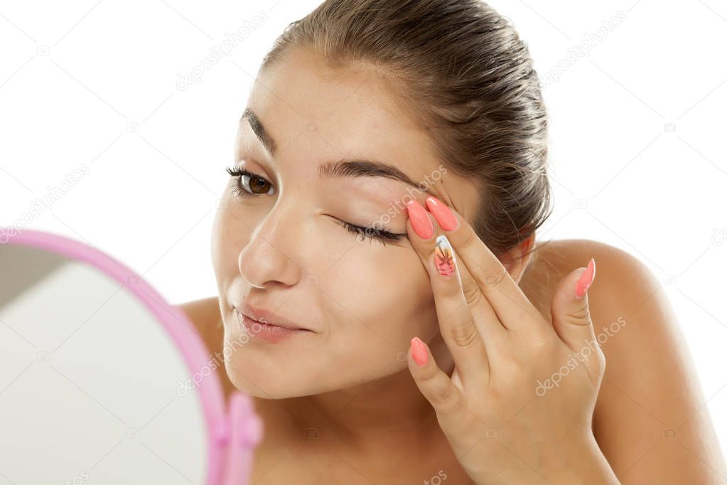 Young beautiful woman applying concealer around the eyes