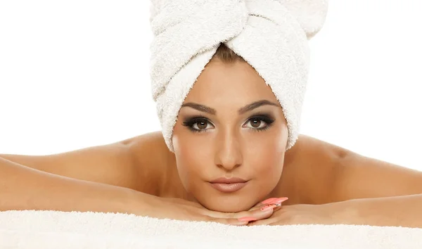 年轻美丽的女人在白色的背景上用毛巾摆在她的头上 — 图库照片