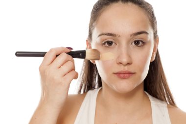 Genç kadının yüzünde bir fırça ile sıvı temel uygulama