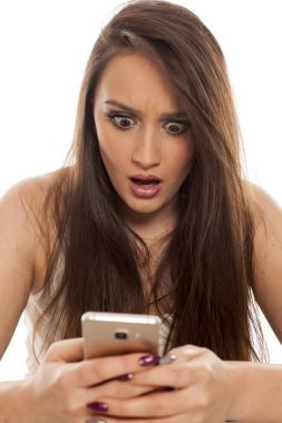 Şok genç kadın beyaz bir arka plan üzerinde onun smartphone vasıl arıyor