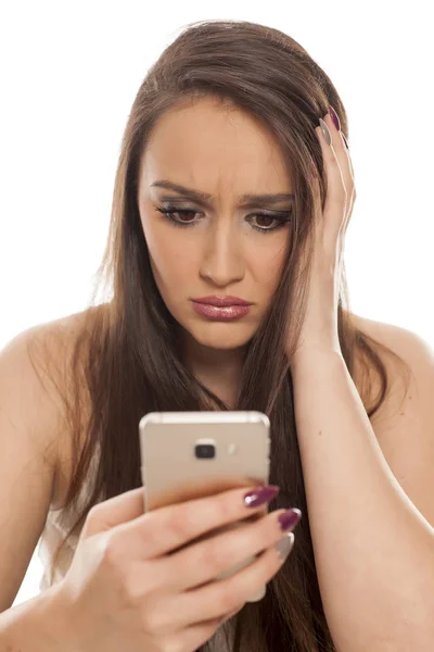 Mujer Joven Triste Mirando Teléfono Inteligente Sobre Fondo Blanco — Foto de Stock