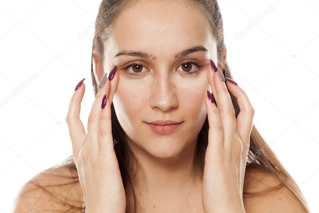 Young woman applying concealer under her eyes with her fingers