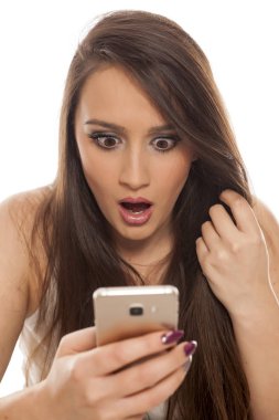 Şok genç kadın beyaz bir arka plan üzerinde onun smartphone vasıl arıyor