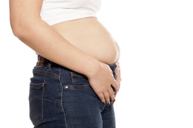 Woman showing her bloated stomach after eating clipart