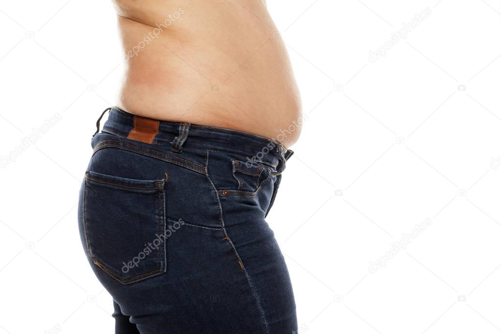 Fat deposits on the waist and stomach of a young woman on a white background