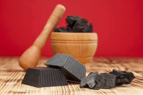 Two hand made black activated charcoal soaps on red background