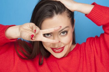 Mavi bir arka plan üzerinde kırmızı bluz yapımı zafer jest olarak güzel kadın