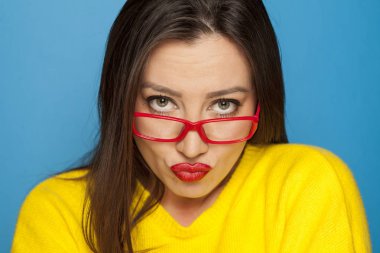 Mavi bir arka plan üzerinde kırmızı çerçeve gözlük güzel kadın