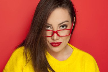 Kırmızı bir arka plan üzerinde kırmızı çerçeve gözlük güzel kadın