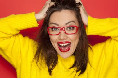 Kırmızı bir arka plan üzerinde kırmızı çerçeve gözlüklü güzel mutlu kadın