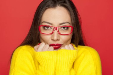 Kırmızı bir arka plan üzerinde kırmızı çerçeve gözlük güzel kadın