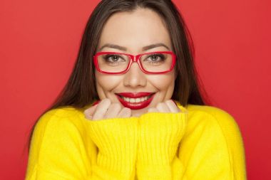 Kırmızı bir arka plan üzerinde kırmızı çerçeve gözlük gülümseyen güzel kadın