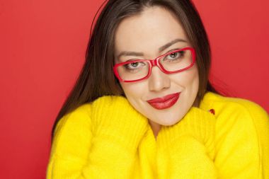 Kırmızı bir arka plan üzerinde kırmızı çerçeve gözlük gülümseyen güzel kadın