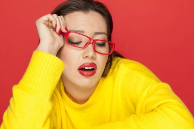 Kırmızı bir arka plan üzerinde kırmızı çerçeve gözlük güzel kadın