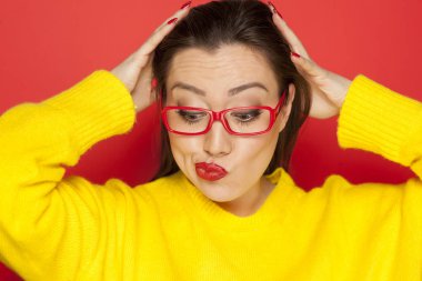 Kırmızı bir arka plan üzerinde kırmızı çerçeve gözlüklü güzel merak kadın