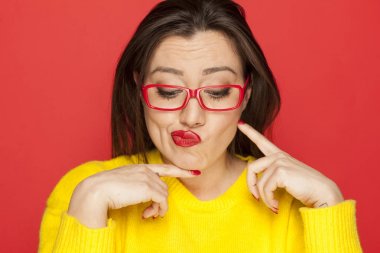 Kırmızı bir arka plan üzerinde kırmızı çerçeve gözlüklü güzel merak kadın