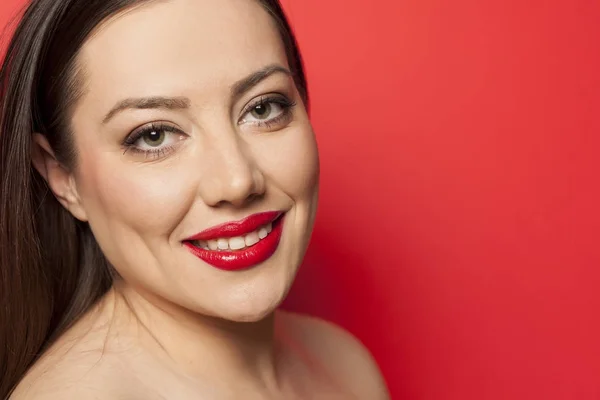 Retrato Una Hermosa Mujer Sonriente Con Maquillaje Sobre Fondo Rojo — Foto de Stock