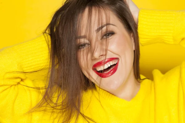 Beautiful happy woman in yellow sweater on a yellow background