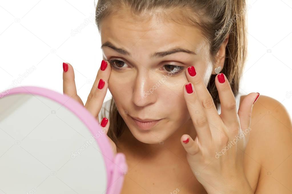 Young women applying concealer under her eyes with her fingers
