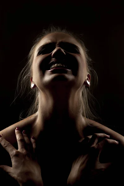 Woman in shadow screaming on a dark background