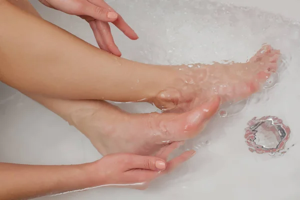 Woman touching her legs in the tub with water