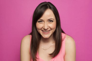 Pembe bir arka plan üzerinde gülümseyen genç kadın