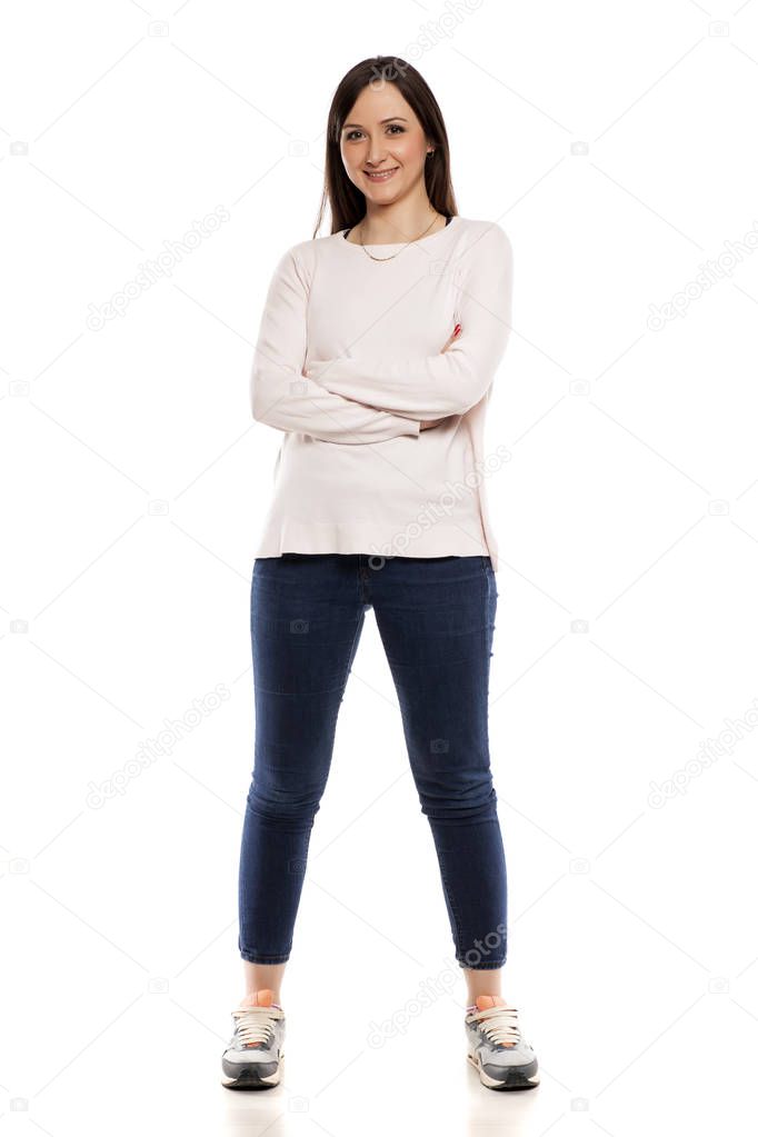 Young woman in jeans, blouse and sneakers on a white background