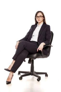 Beyaz bir arka plan üzerinde poz bir ofis koltuğu içinde olumlu iş kadını