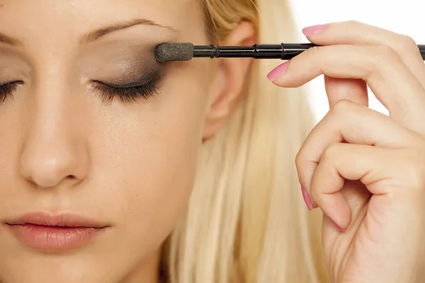 Wanita Pirang Muda Menerapkan Eye Shadow Dengan Kuas Makeup — Stok Foto