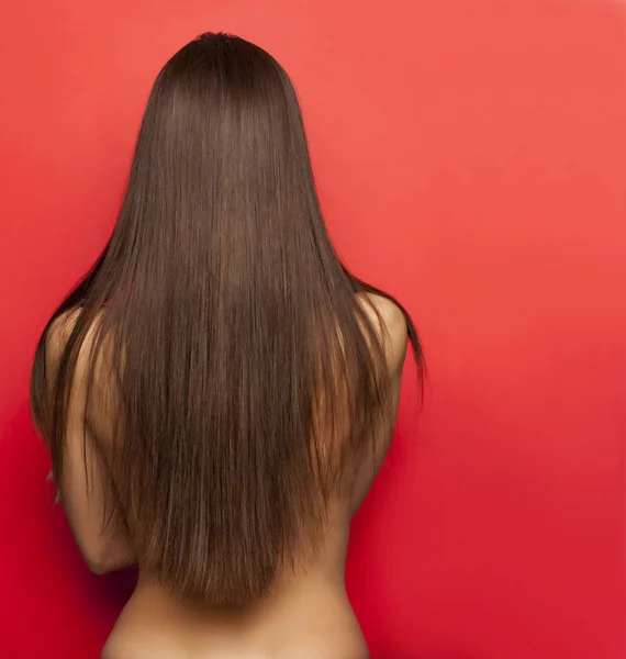 在红色背景长直的头发的妇女的后面看法 — 图库照片