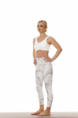 Yoga, spor, eğitim ve yaşam tarzı kavramı. Beyaz bir arka plan üzerinde beyaz spor giyim bir genç güzel kadın portresi.