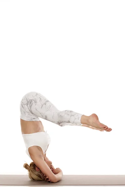 Side plank pose, Vasisthasana. Yoga, sport, training and lifestyle concept - Young blonde woman in white sportswear doing yoga exercise.