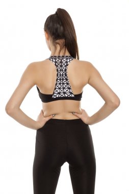 Beyaz bir arka plan üzerinde spor içinde genç bir kadın arkadan görünüm