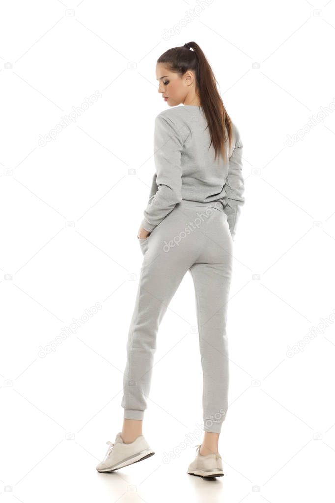 Young beautiful woman in gray tracksuits on a white background