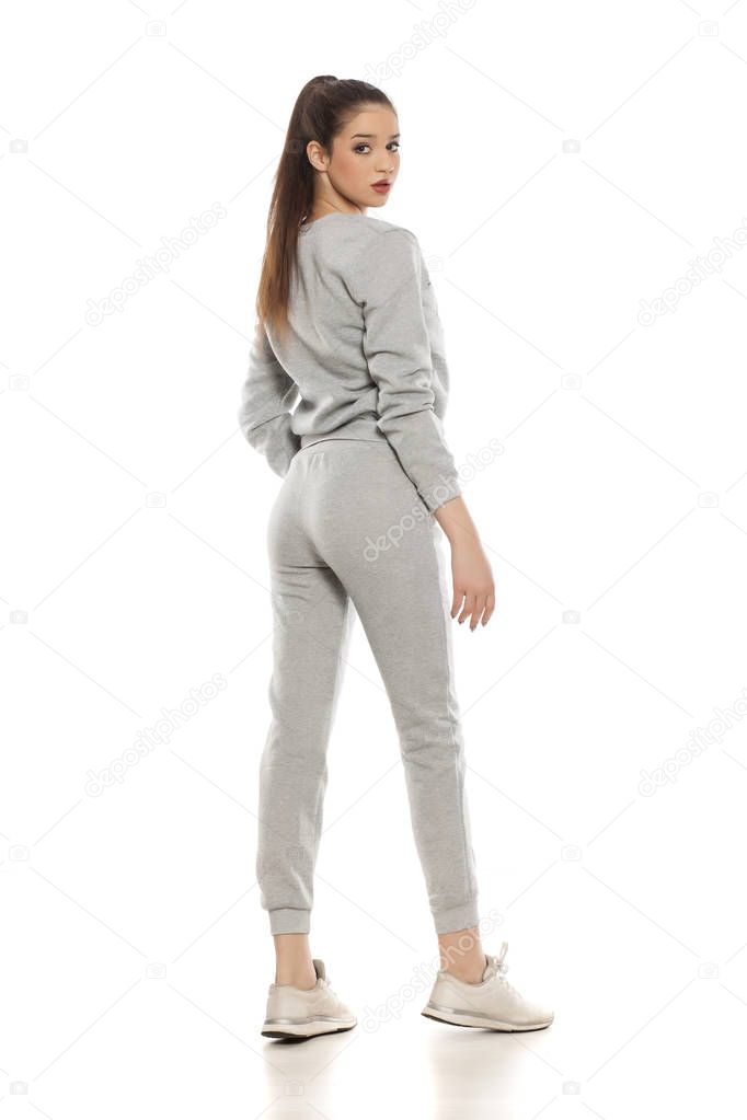 Young beautiful woman in gray tracksuits on a white background