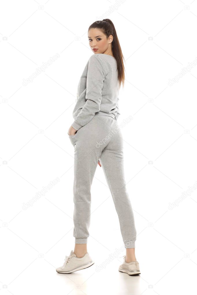 Young beautiful woman in gray tracksuits on a white background