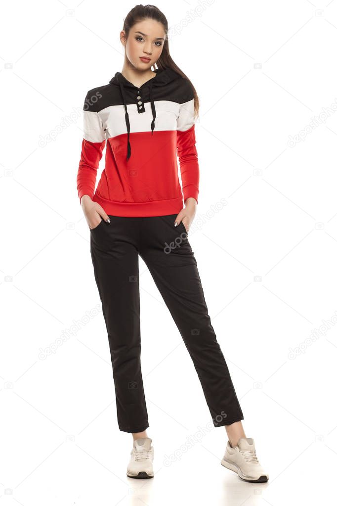 Young beautiful woman in black and red tracksuits on a white background