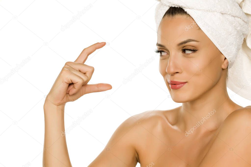 Young beautiful advertizing woman with towel on her head on white background