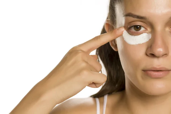 Young Woman Applying Face Cream Heer Eyes White Background — Stock Photo, Image